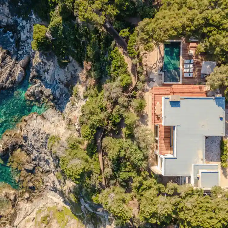 Vue aérienne d'un domaine de prestige aménagé par L'Empreinte Verte dans le Var : intégration paysagère d'une villa et piscine en bord de falaise, respectant la végétation naturelle et le littoral.