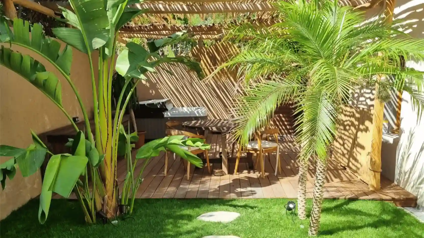 Aménagement paysager en bord de mer à Hyères : jardinière de plantes exotiques (Yuccas, Strelitzias), brise-vue en bois et bois flotté décoratif face à la plage.