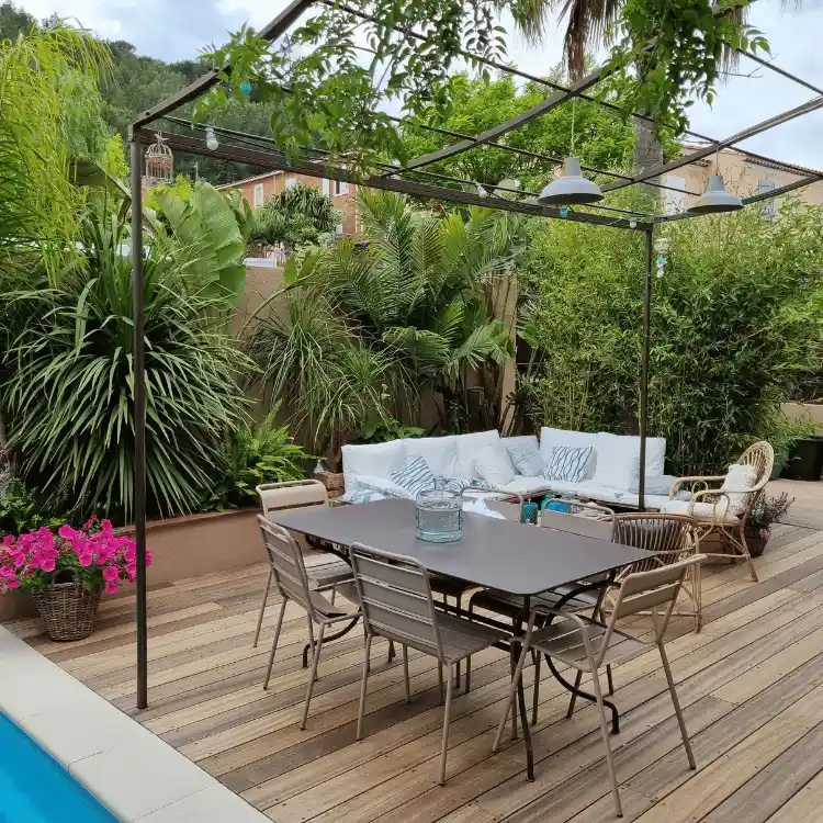 Réalisation paysagère haut de gamme dans le Var : Aménagement d'une piscine rectangulaire intégrée dans une grande terrasse en bois, avec un jardin contemporain structuré, gazon et pas japonais géants.