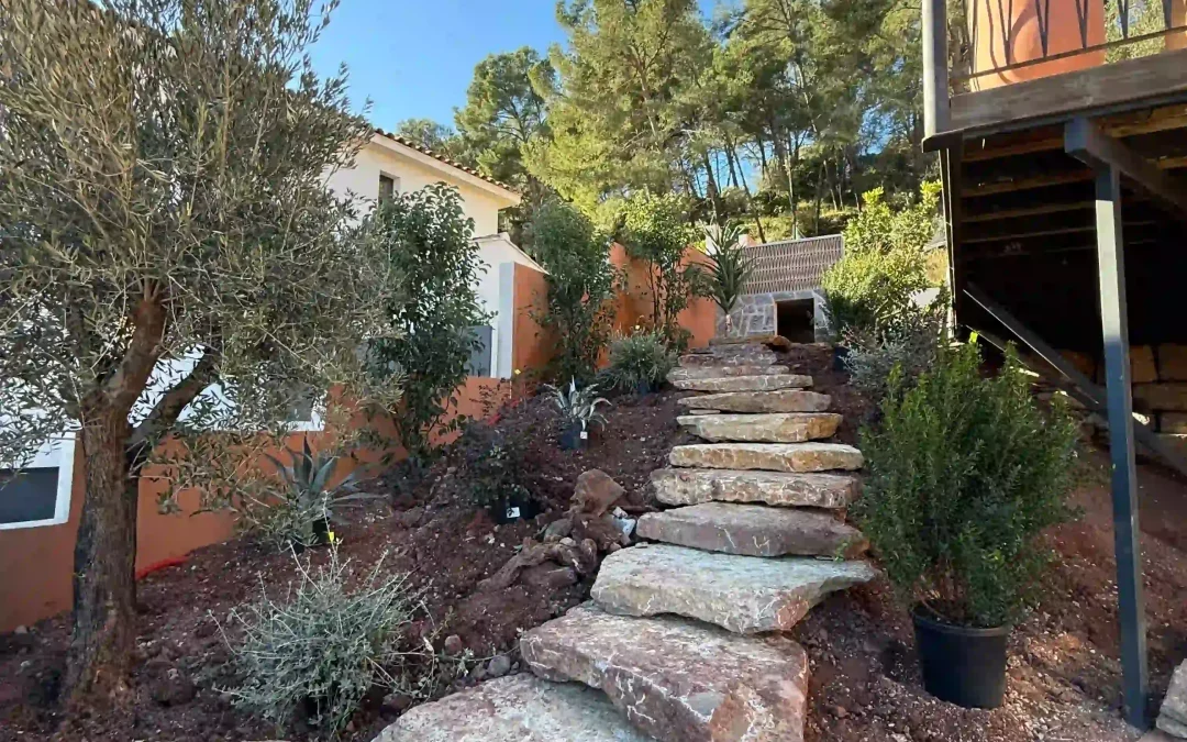 Escalier en pierre sur terrain en pente avec massifs stabilisés pour limiter le ruissellement et la boue.